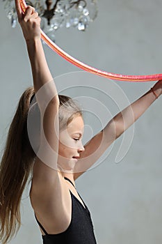 girl gymnast in a black leotard with a with hoop on a grey background. Rhythmic gymnastics concept