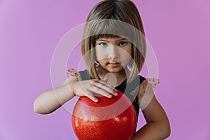 Girl gymnast in a stylish leotard posing with a red gymnastic ball