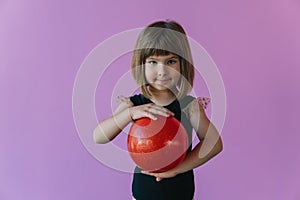 Girl gymnast in a stylish leotard posing with a red gymnastic ball