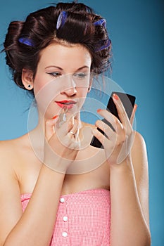 Girl in hair curlers applying red lipstick