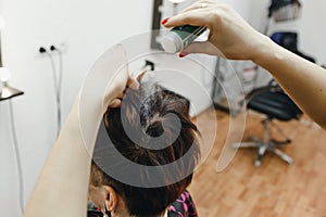 The girl hairdresser carefully makes a hairstyle for her client