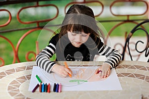 Girl in Halloween outfit draws pumkin