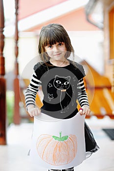 Girl in Halloween outfit shows her pumkin drawing photo