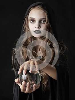 Girl in Halloween witch costume with crystal ball