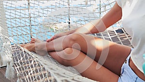 Girl on the hammock to put a cream on legs. beautiful woman skin care.