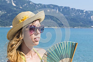 Girl with hand cooling fan at the beach. Summer vacation backgro