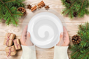 Girl hand hold Top view. Empty white plate on wooden background with christmas decoration. New Year concept