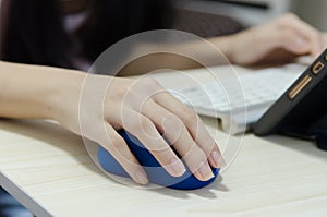 Girl hand holding a blue computer mouse.Online learning at home
