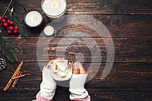 Girl hand holding cup of hot chocolate on white table with rustic decoration
