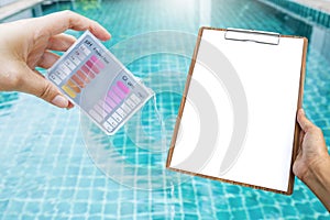 Girl hand holding swimming pool tester and blank report on wooden clipboard