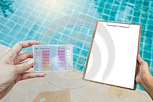 Girl hand holding water testing test kit with blank report sheet in girl hand over swimming pool background