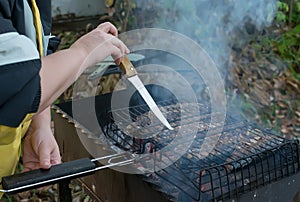 The girl hand holds a knife and pokes it into the fish