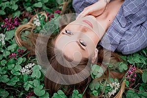 A girl with hand is lying on the grass in flowers