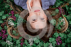 A girl with hand is lying on the grass in flowers