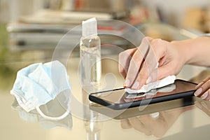 Girl hand with mask disinfecting with sanitizer phone screen photo