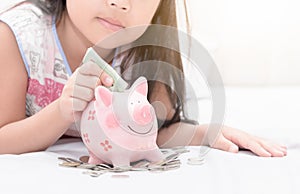 Girl hand put money to piggybank on bedroom