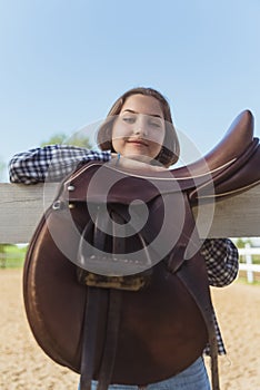 Girl With Hand Resting On The Fence A Leather Saddle Hanging On The Wooden Fence