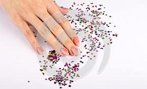 Girl hand scatters, colored sequins of various shapes on a white background