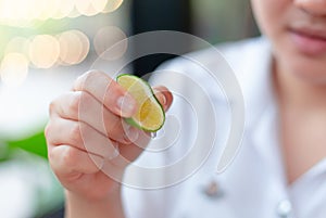 Girl hand squeezing a little lime lemon juice