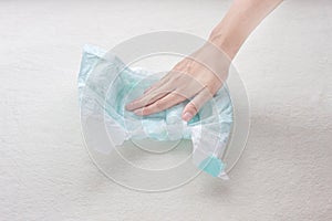 Girl hand touches the moisture absorbency of a baby diaper, close-up