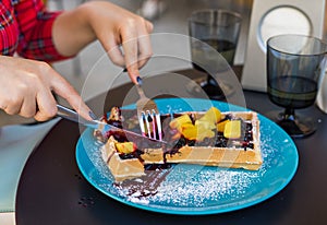 Girl hands cutting belgium waffles with fruite. Girl hands with cutlery