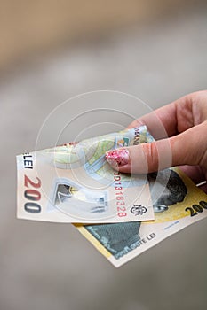 Girl hands giving money. Holding LEI banknotes on a blurred background, Romanian currency