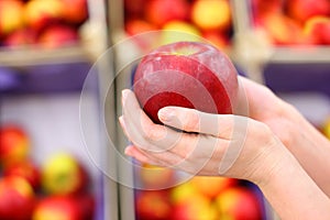 Girl hands hold big red apple in shop photo