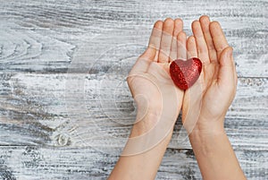 Girl Hands Holding a Sparkling Red Heart. Top View. Valentine`s Day. Mother`s Day. Love and Parenting Concept. Copy