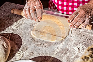 Girl hands keep rolling pin with flour on table, baking background, top view. Man rolling out dough on kitchen table