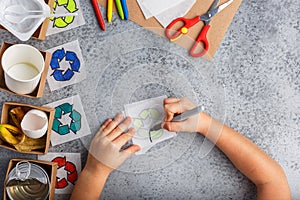 Girl hands are making recycling game in paper on grey background colourful