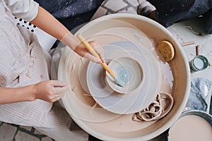 Girl hands painting clay bowl on a pottery wheel in a private workshop