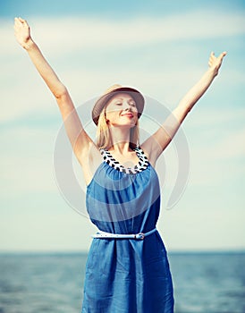 Girl with hands up on the beach