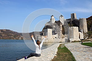 The girl with hands up looks at the Golubac fortress photo