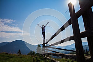 Girl with hands up on top of mountains