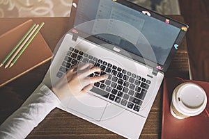 Girl hands working on modern laptop. Desktop, book, pen, coffee on  background