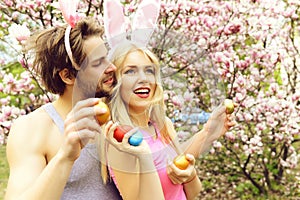 Girl and handsome man with bunny ears holding eggs