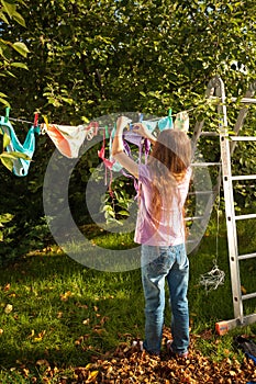 Girl hanging clothes on clothesline at garden