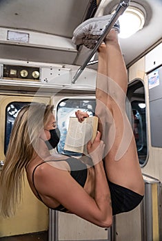 Girl hanging by feet upside down in the subway with mask and reading book. Concept of using every single possibility and