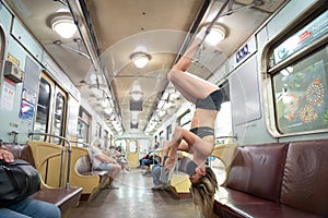 Girl hanging by feet upside down in the subway with mask and reading book. Concept of using every single possibility and