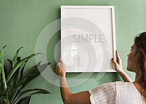 Girl hanging a frame on a green wall photo