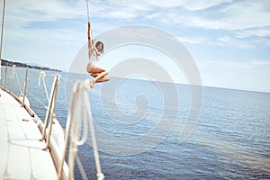 Girl hanging out, having fun and enjoying summer days jumping from sailing boat in sea