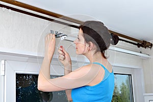 Girl hangs vertical blinds, tighten with a screwdriver, br