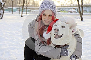 The girl happily communicates with the dog in the hat of Santa Claus photo