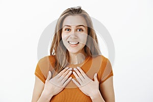 Girl happy to be honored with gold medal. Surprised pleased attractive woman with blond hair, holding palms on chest and