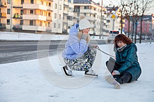 A girl has fallen in the snow and is holding her leg.