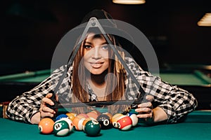 A girl in a hat in a billiard club with balls in her hands.Playing billiards