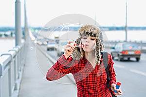 Girl in a hat blowing bubbles on the bridge