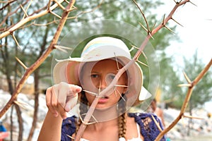 The girl in the hat in the dangerous bushes. Little girl and spikes. photo