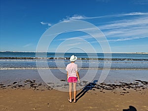 Girl with hat in front of the sea, on a sandy beach. Valdelagrana Beach photo
