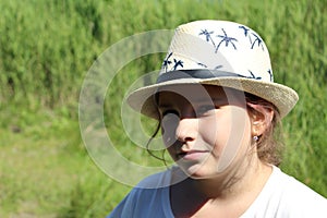 Girl with a hat on a green background on a Sunny day